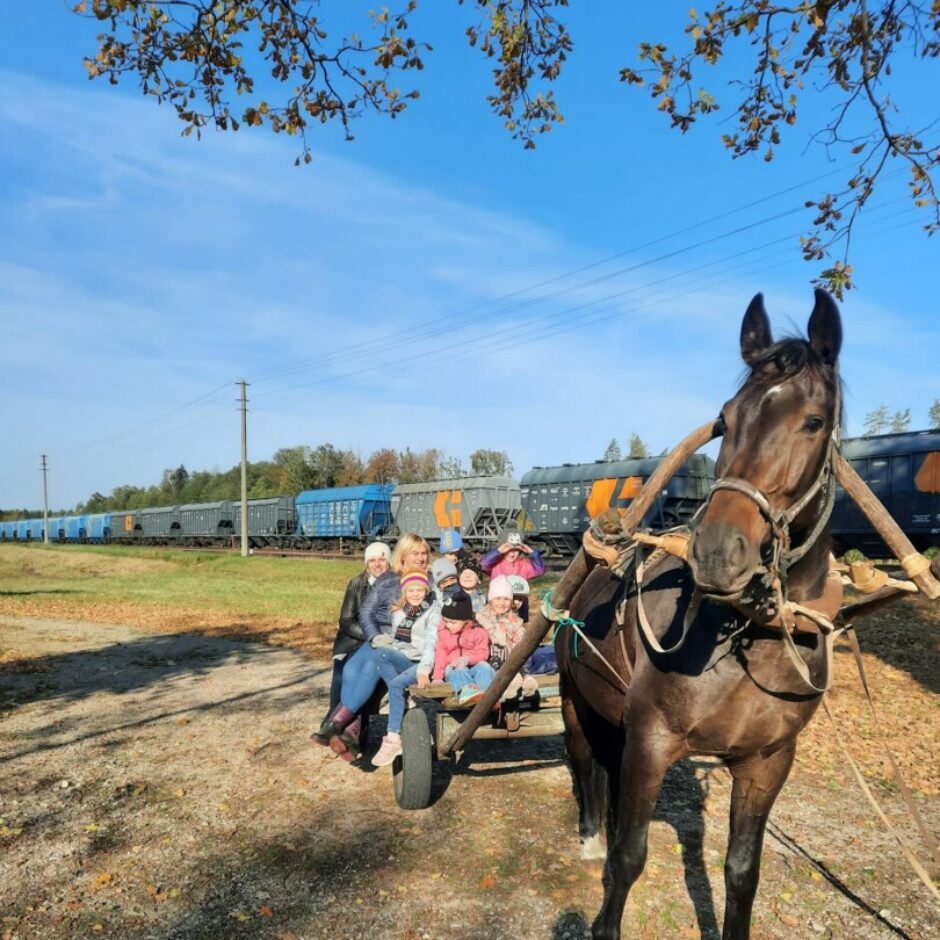 Bērni un skolotājas sēž zirga ratos.