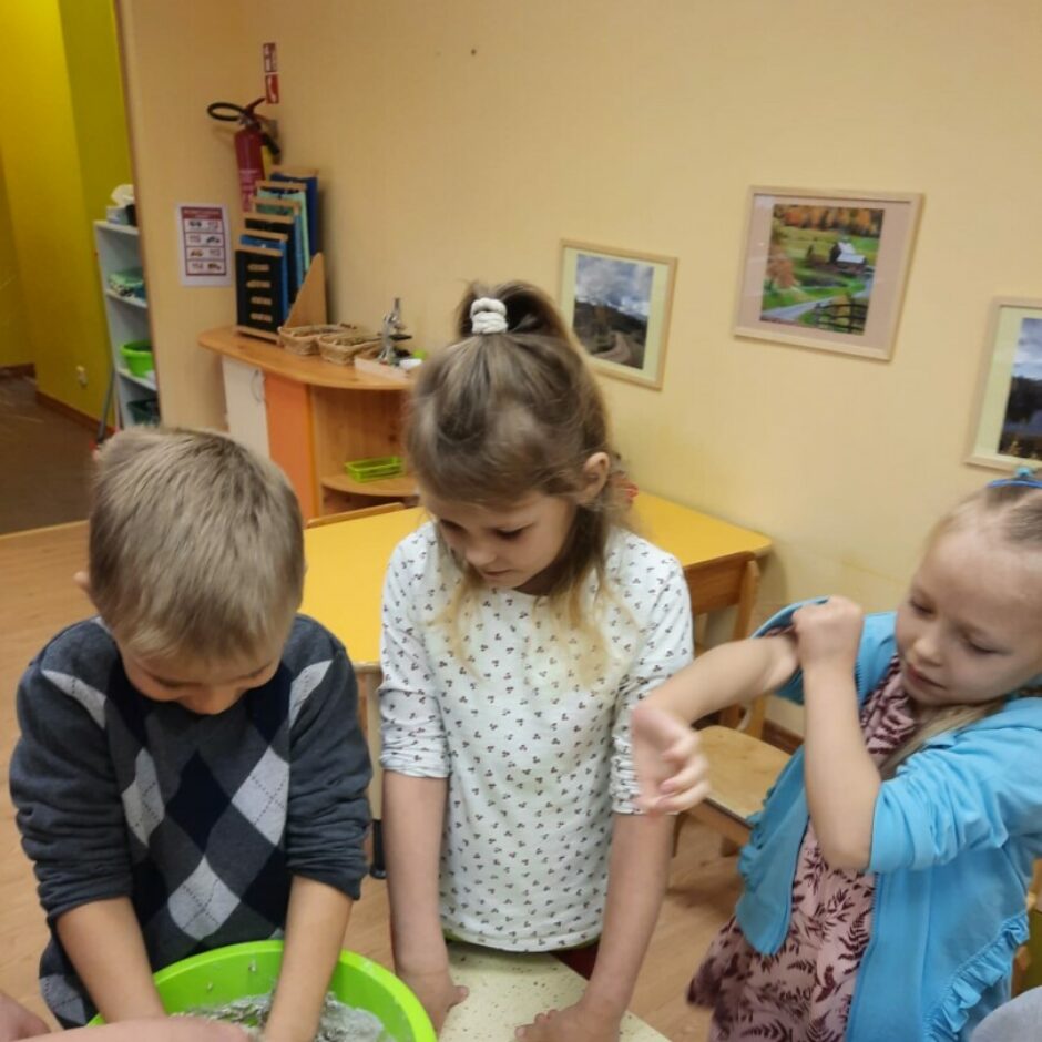 Puisis mīca mīklu, citi bērni vēro.