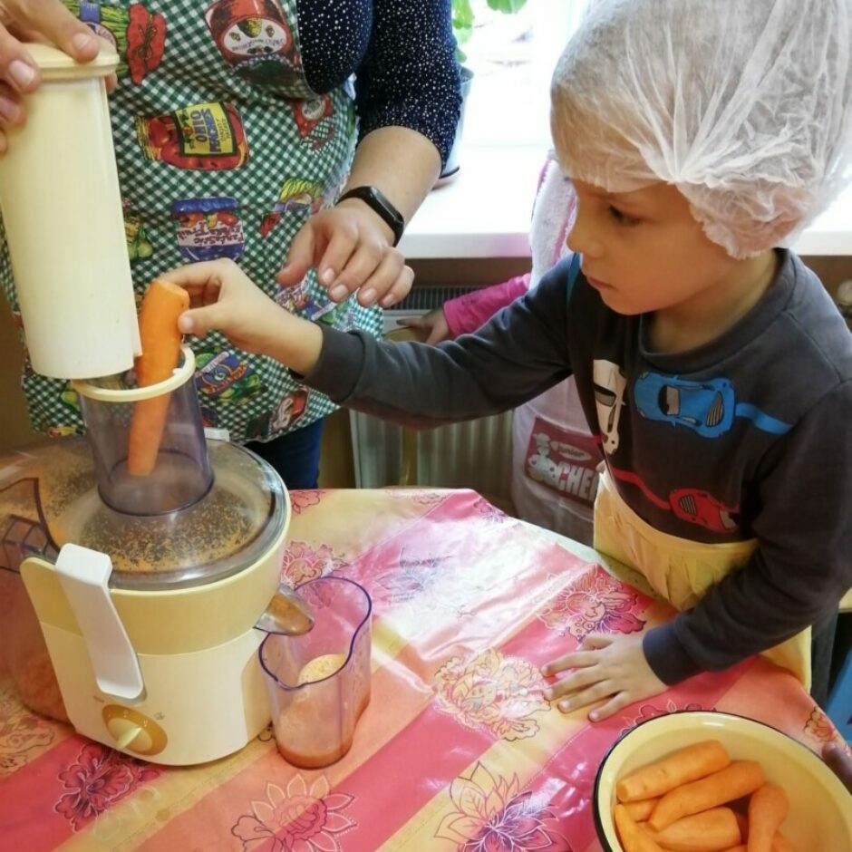 Zēns kopā ar skolotāju spiež burkānu sulu.