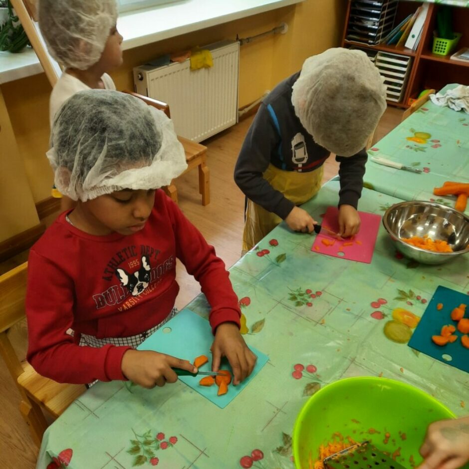 Zēni pie galda griež burkānus.