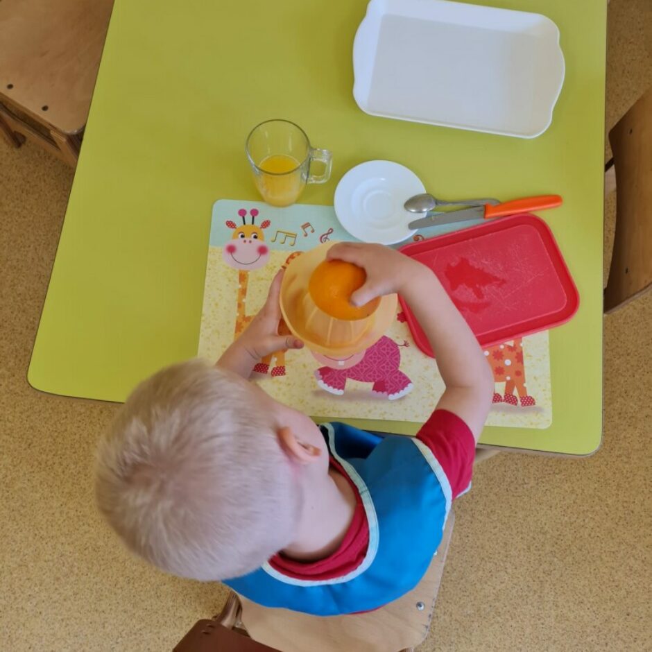 Bērns no pusītes apelsīna spiež sulu.