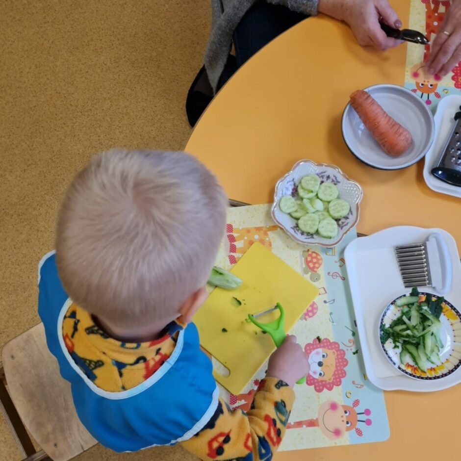 Bērns ar mizojamo nazi mizo gurķi.
