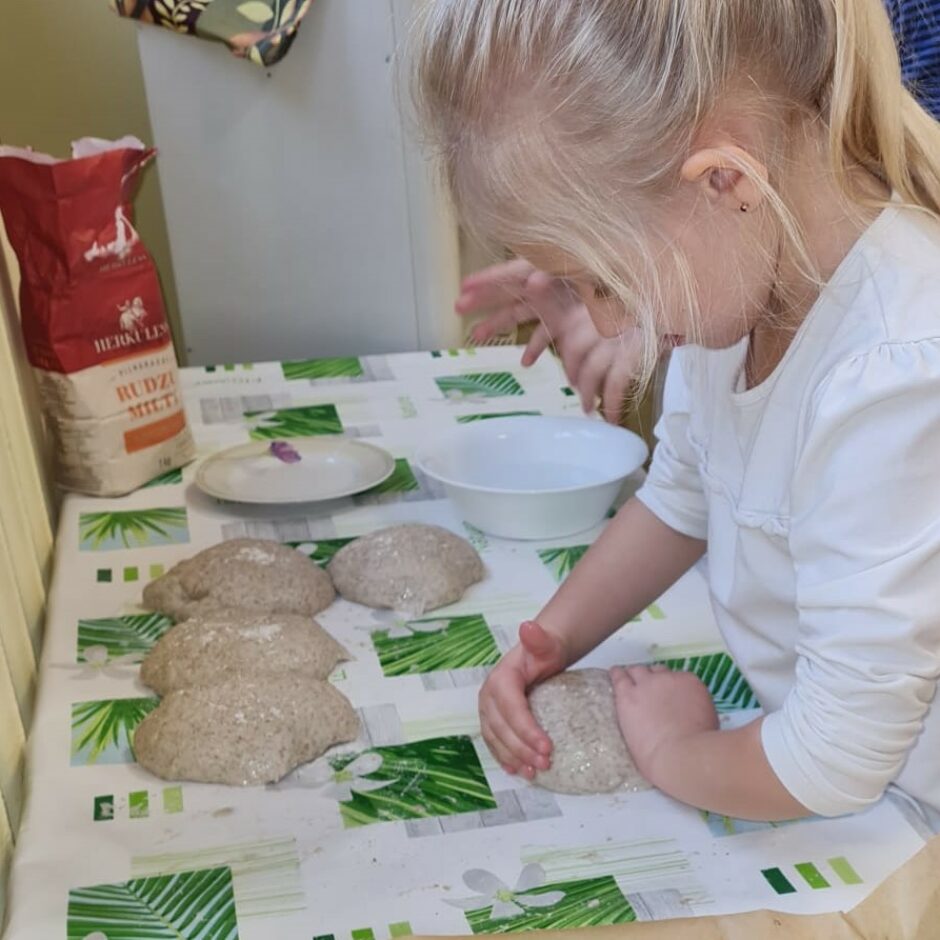 Meitene veido kukulīšus no mīklas.