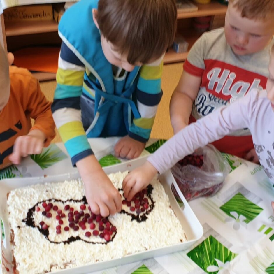 Bērni rotā svētku kūku ar dzērvenēm.