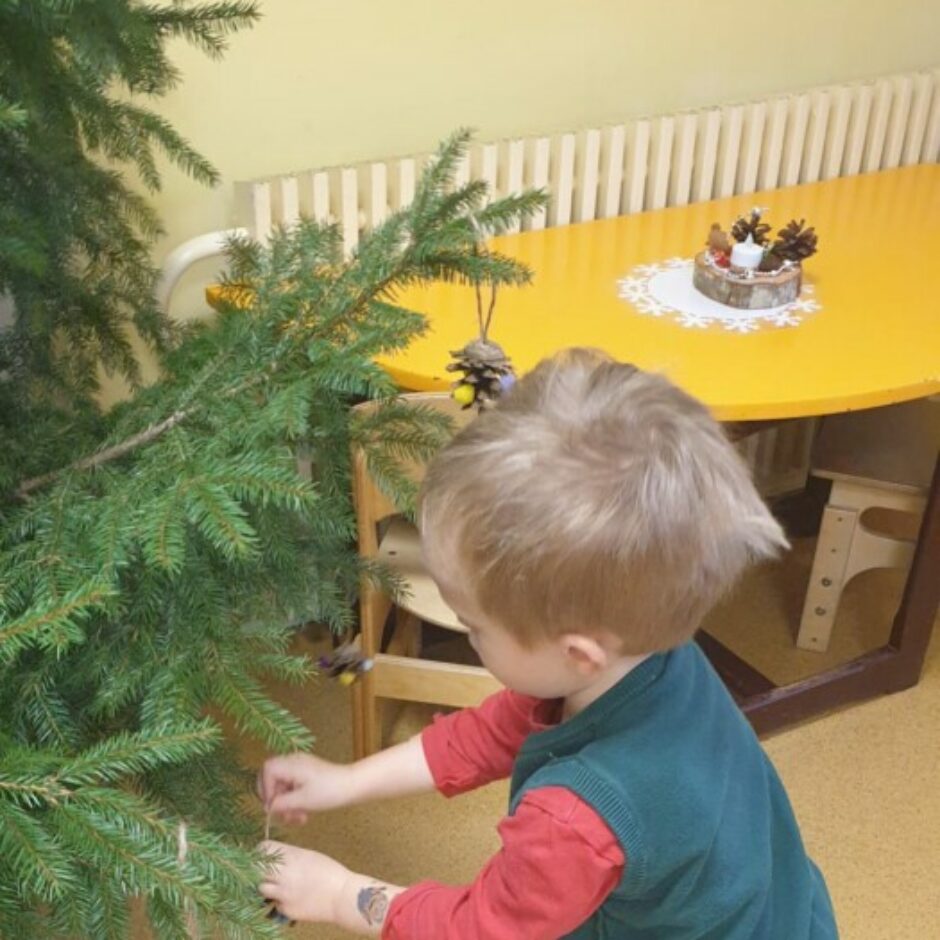 Bērns karina eglītē rotājumu.