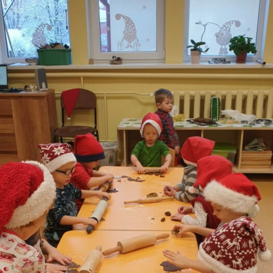 Bērni gatavo piparkūkas - veltnē mīklu un spiež formiņas.