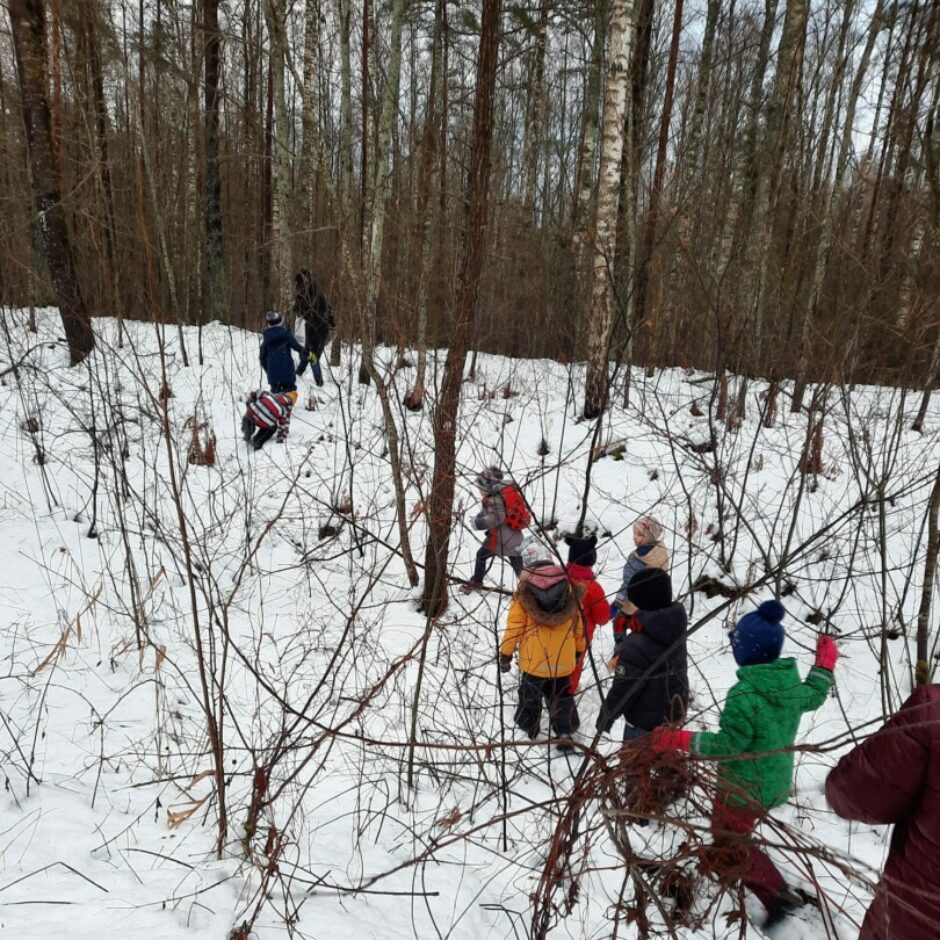 Bērni brien pa piesnigušu mežu.