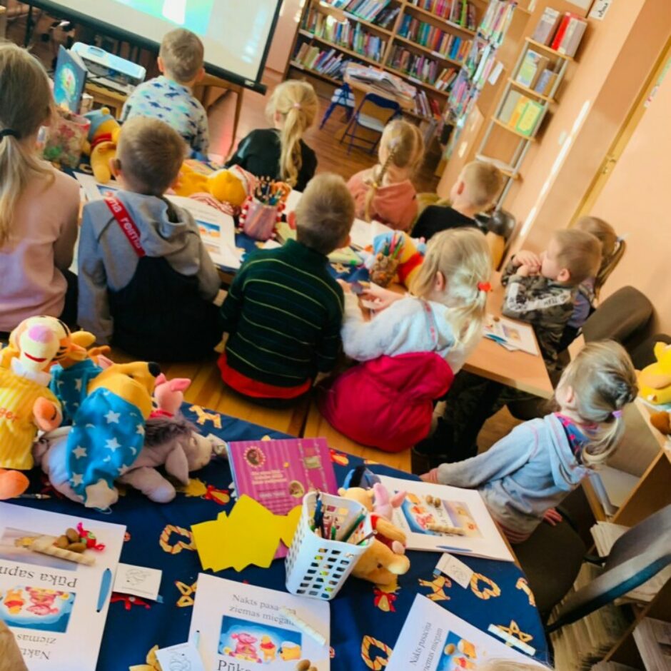 Bērni bibliotēkā skatās filmiņu par Vinniju Pūku.