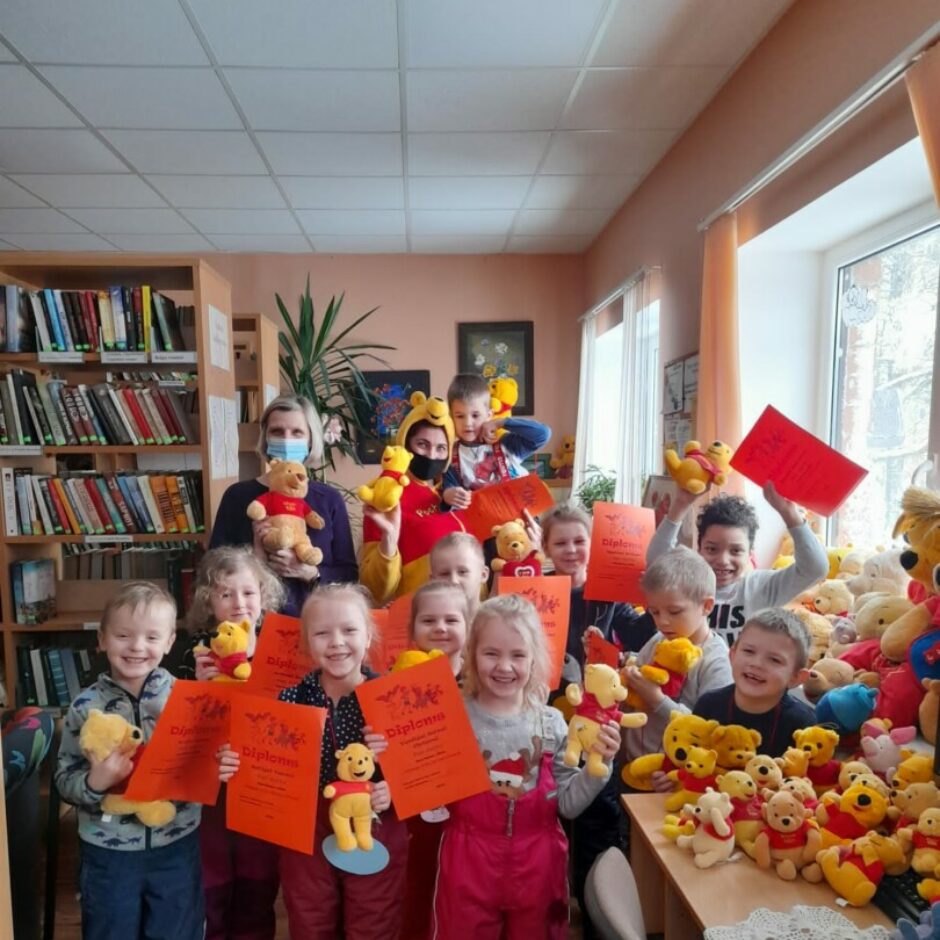 Priecīgi bērni ar diplomiem un Vinnija Pūka rotaļlietām rokās.
