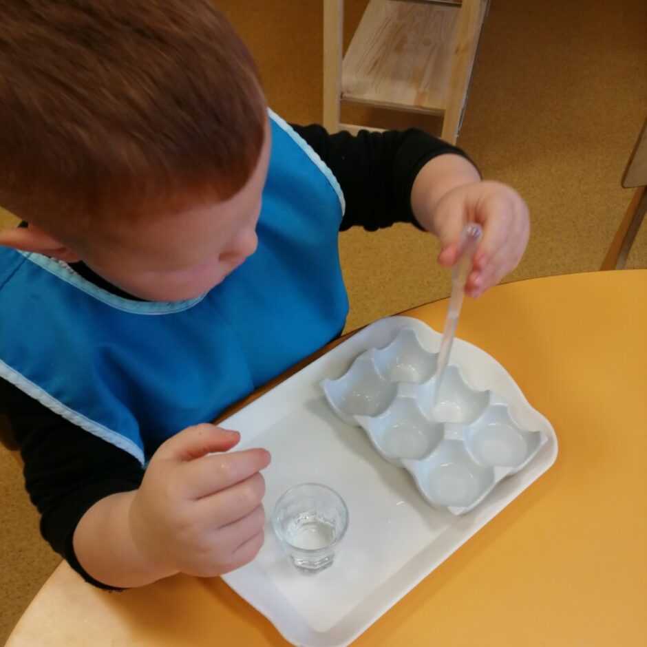 Zēns ar pipeti pārlej ūdeni no glāzes trauciņos.