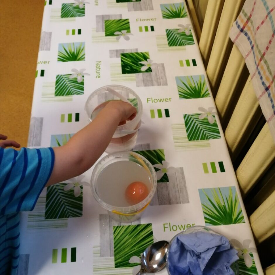 Bērns veic eksperimentu ar olu un sālsūdeni.