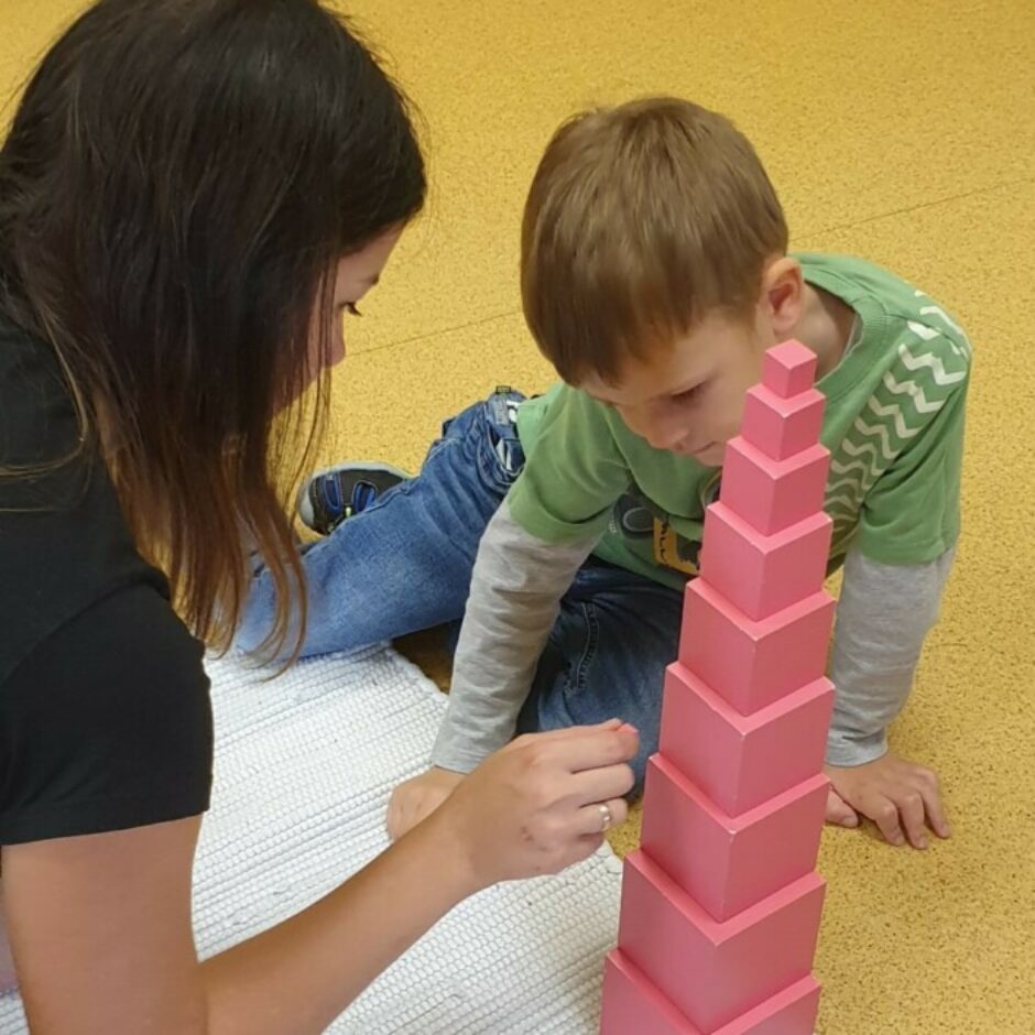 Skolotāja demonstrē zēnam darbu ar Montesori materiālu 