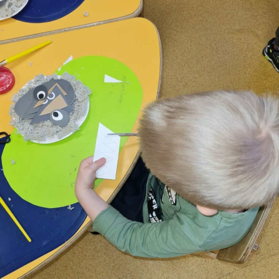 Bērns ar šķērēm griež papīru.