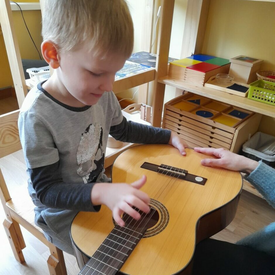 Zēns izmēģina spēlēt uz ģitāras stīgām.