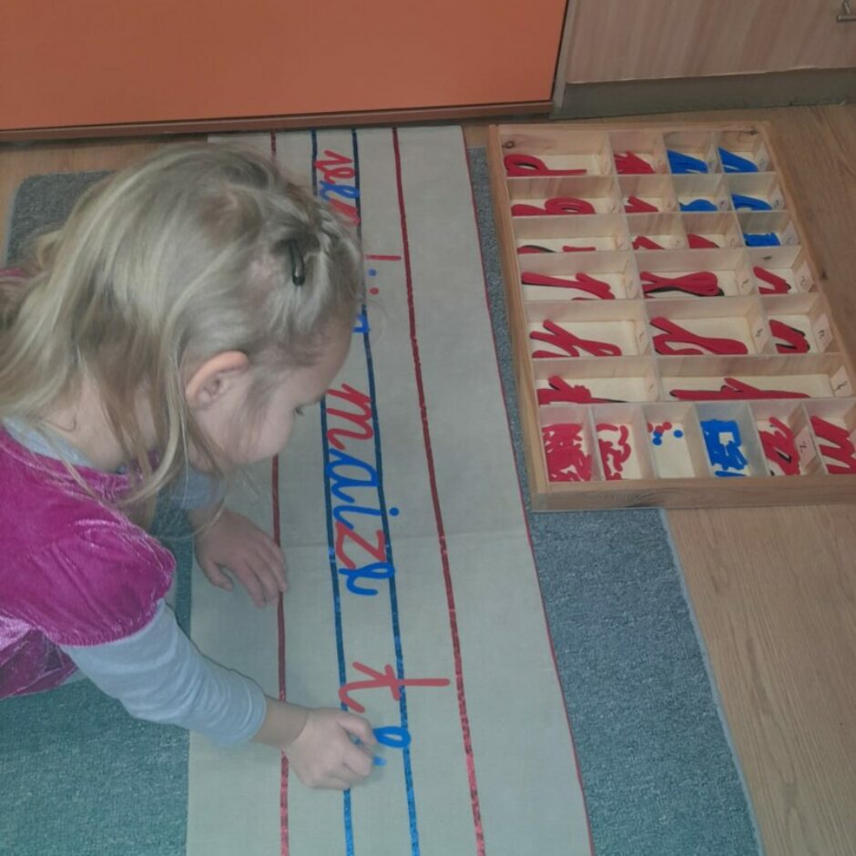 Meitene darbojas ar Kustīgo alfabētu, veidojot no burtiem vārdus.