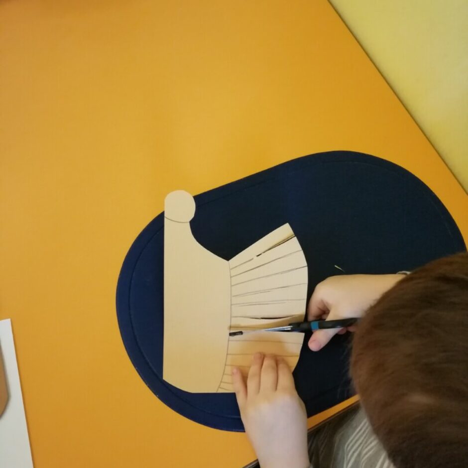 Bērns griež ar šķērēm eža siluetu.