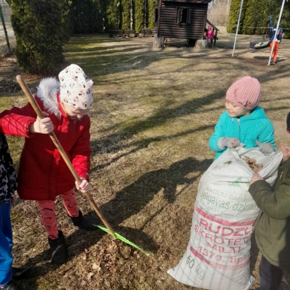 Bērni sakopj laukumiņu - grābj lapas un liek tās maisā.