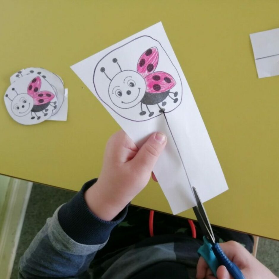 Bērns vingrinās griezt ar šķērēm.