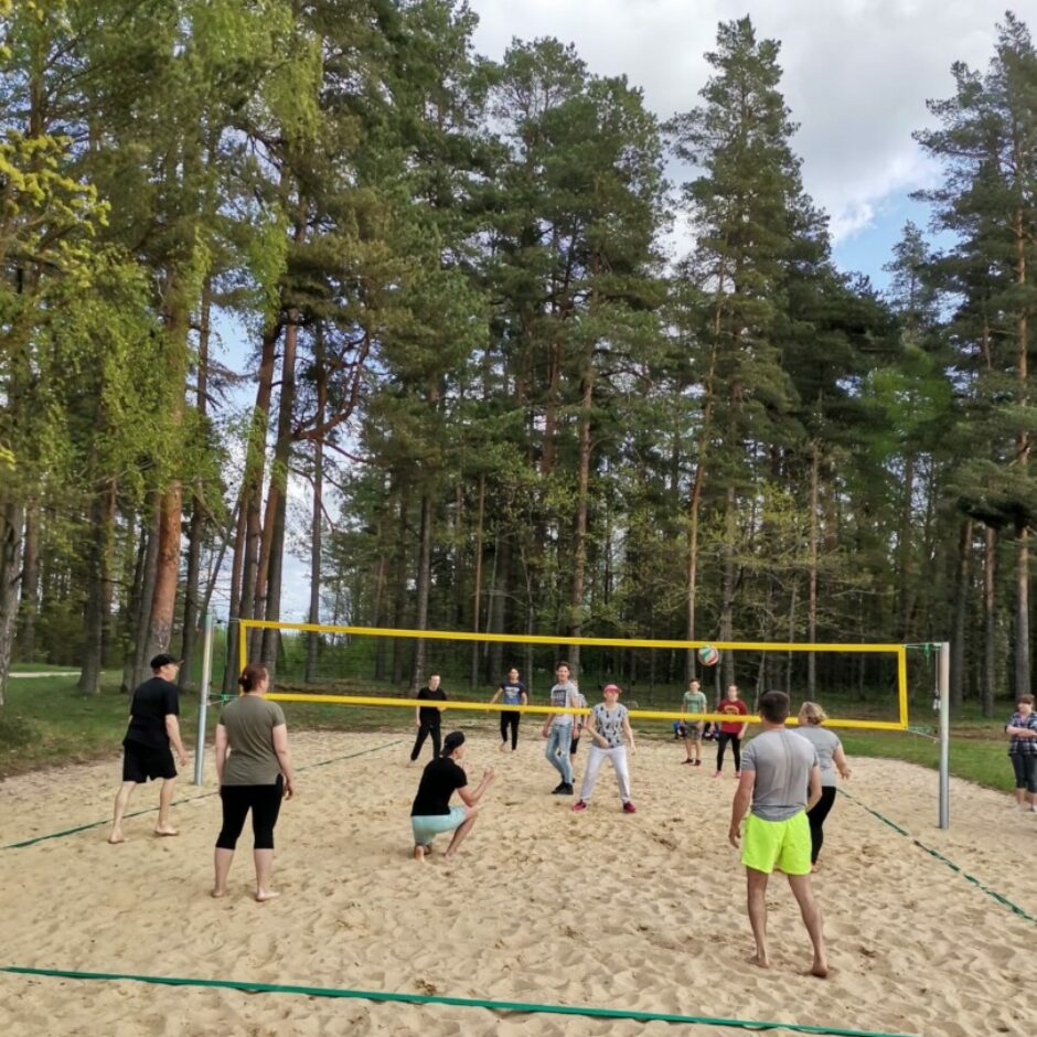 Sievietes un vīrieši spēlē volejbolu