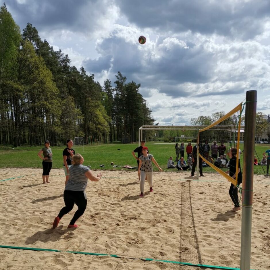 Sievietes un vīrieši spēlē volejbolu