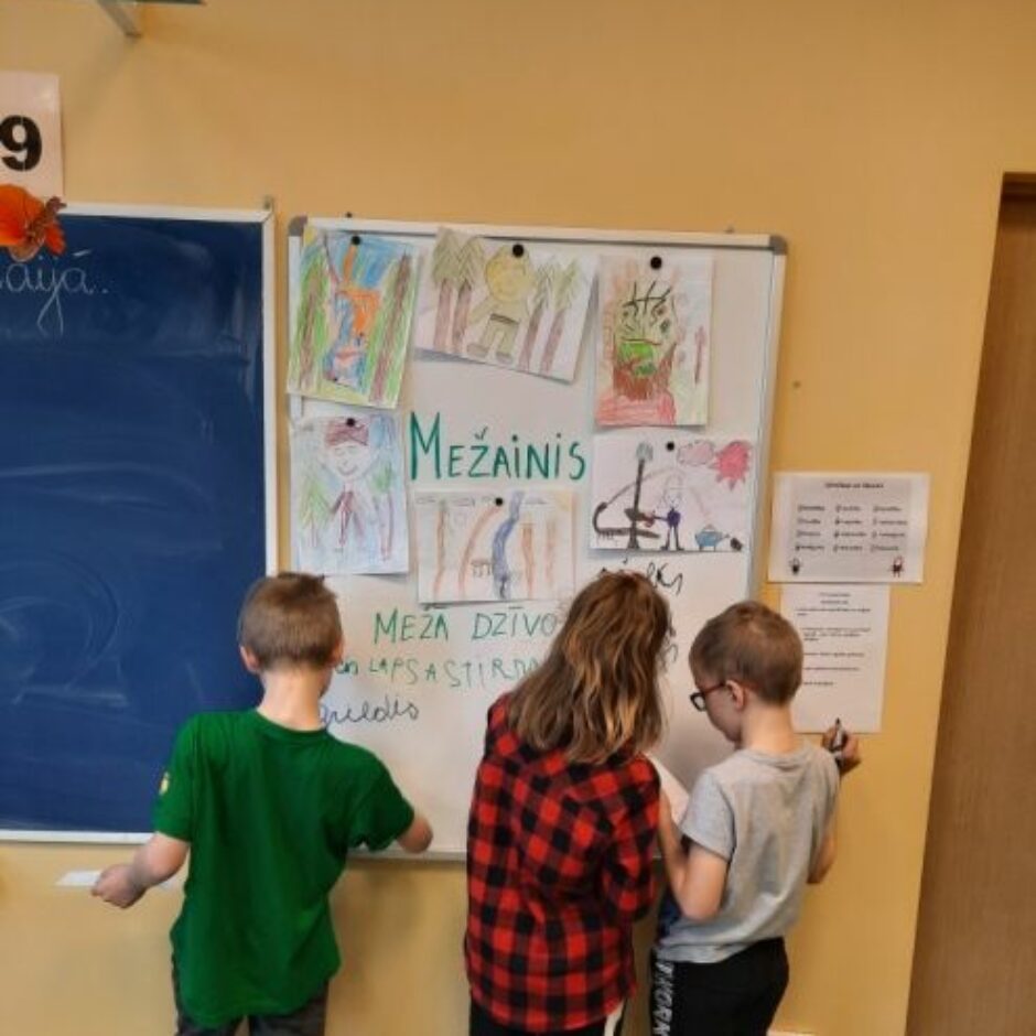 Klasē 3 skolēni pie tāfeles raksta