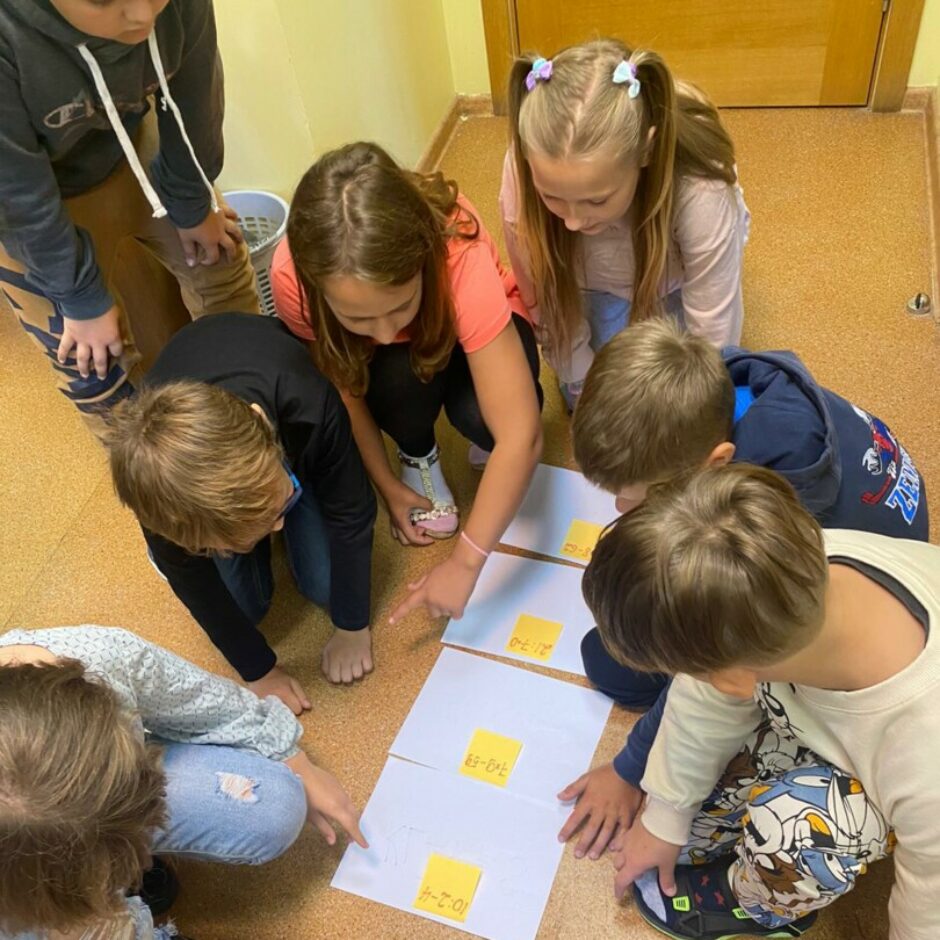 Bērni sēz uz grīdas, pilda uzdevumu