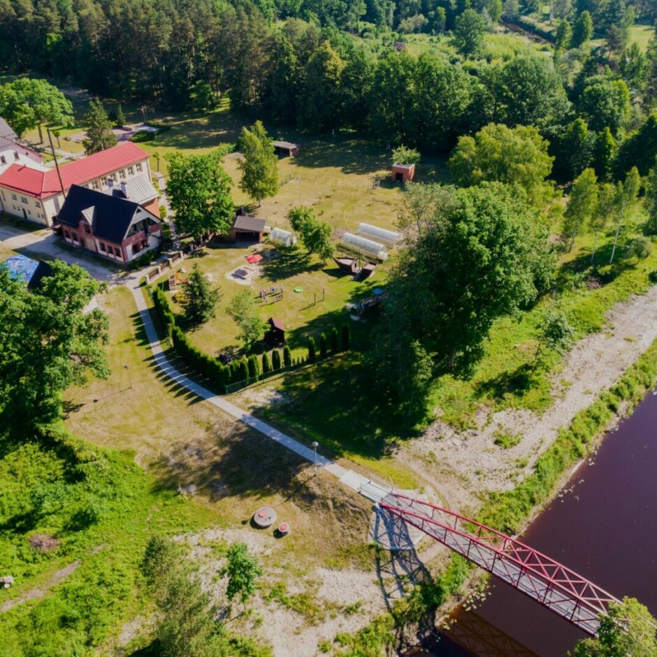 Skats no augšas uz skolu un tās apkārtni - upi, tiltu, mežu, rotaļu laukumu.