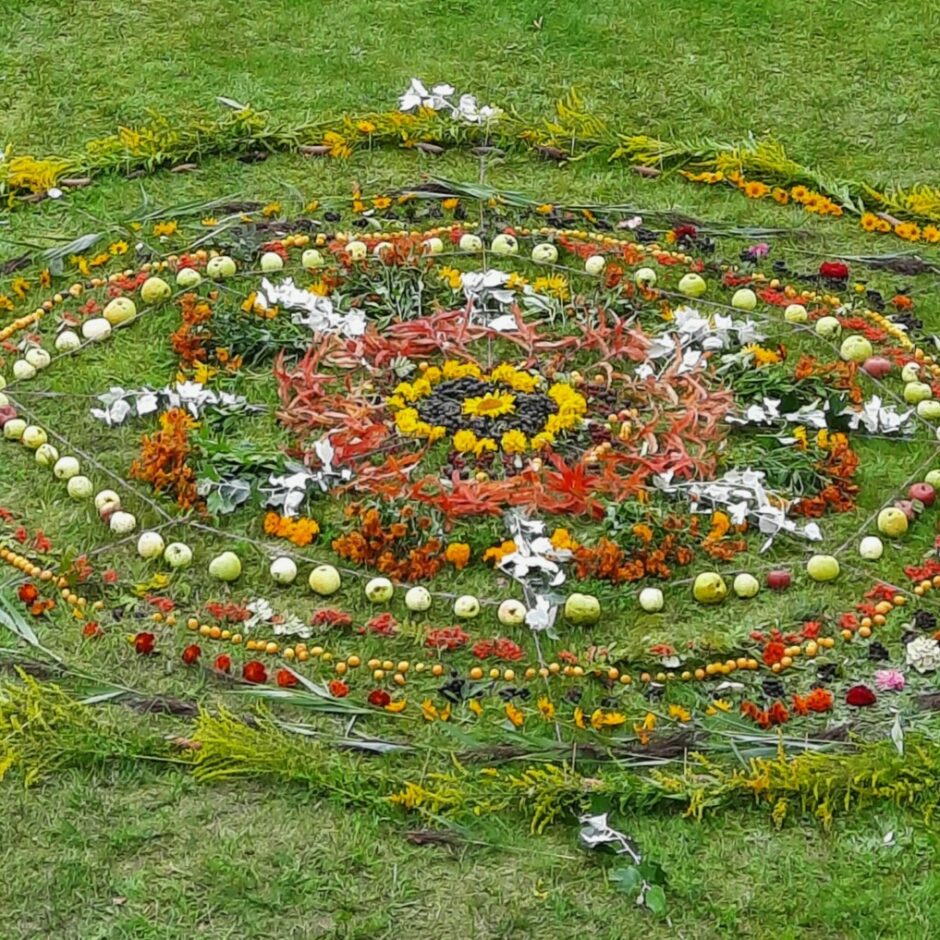 Zālē izveidota mandala no ziediem.