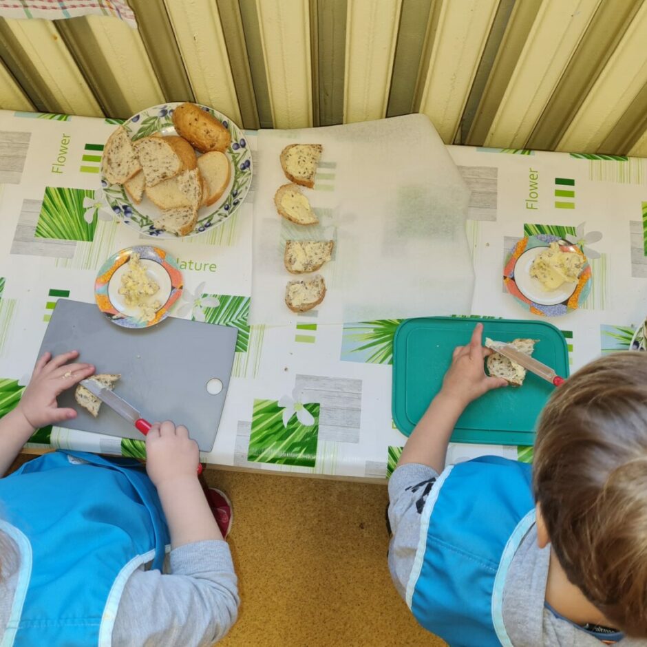 Bērni smērē uz maizītēm sviestu.