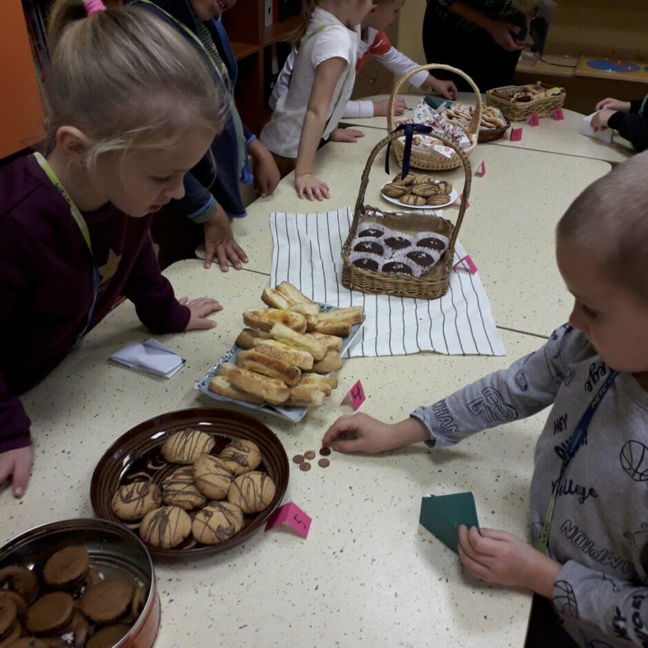 Mārtiņdienas tirdziņa galds ar dažādiem gardumiem. Zēns skaita centus.