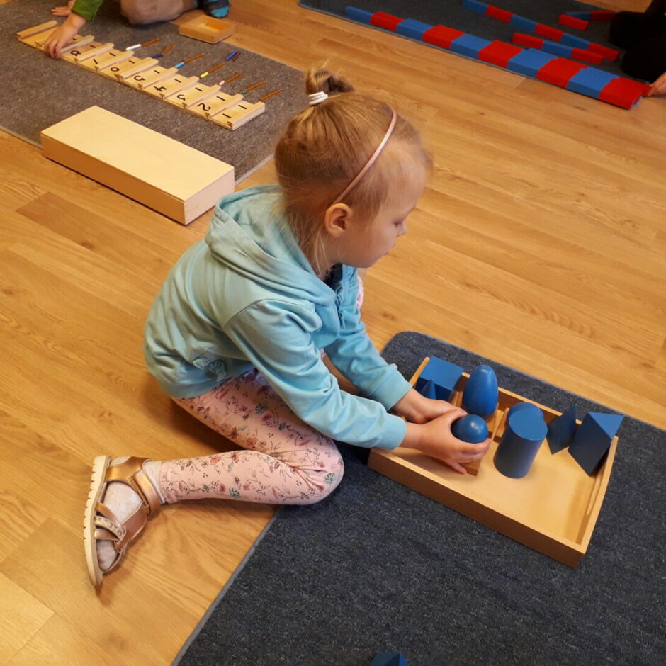 Meitene uz paklāja darbojas ar materiālu 