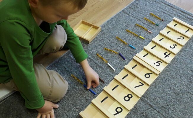 Zēns darbojas ar Montesori materiālu 