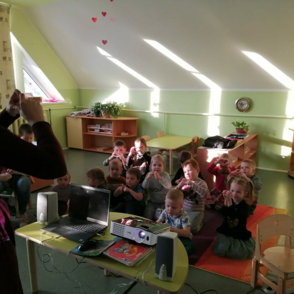 Grupas bērni un skolotāja rāda no plaukstām veidotas sirsniņas.