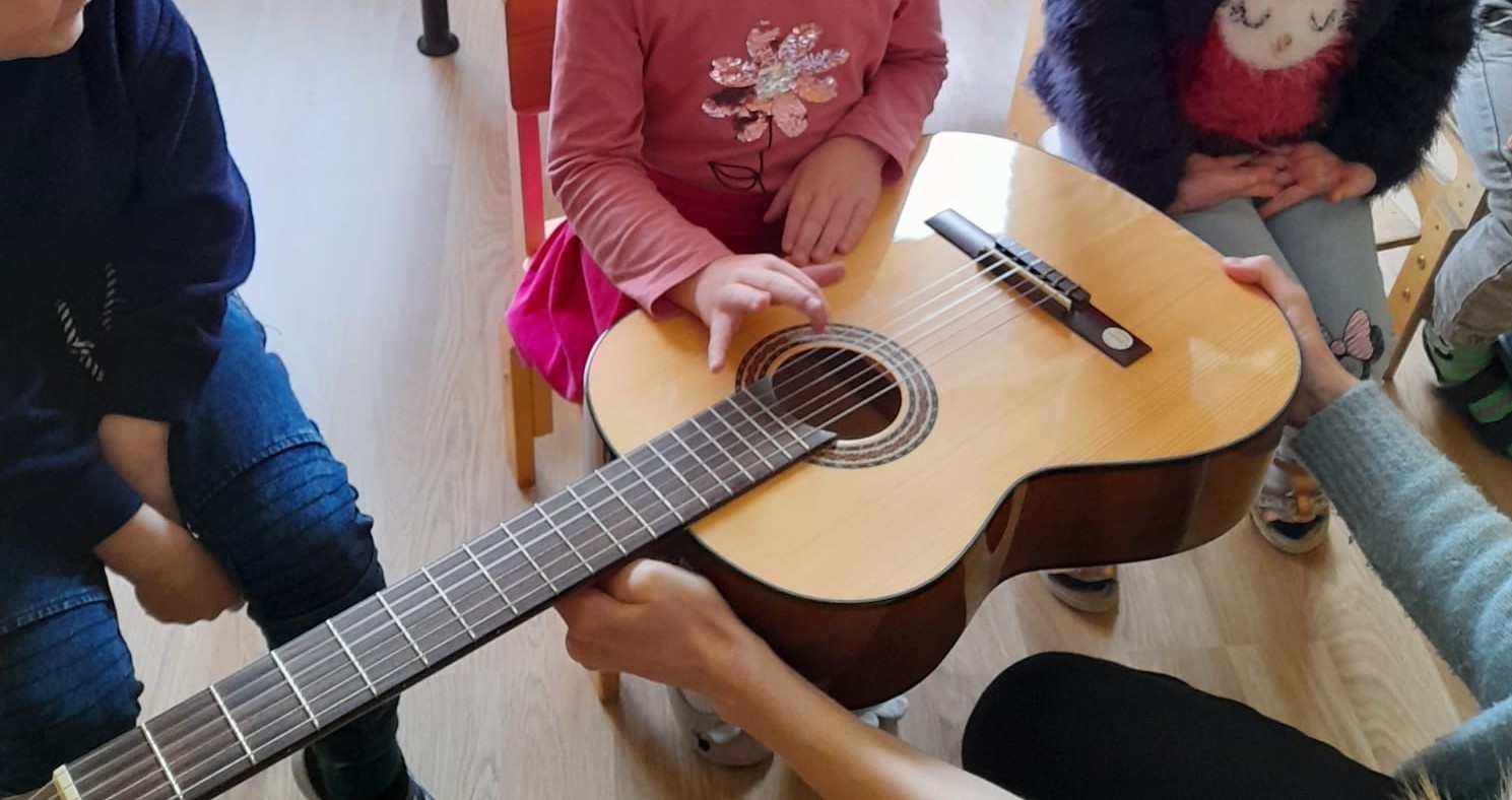 Meitene izmēģina spēlēt uz ģitāras stīgām.