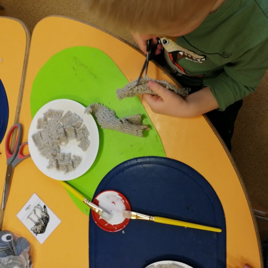 Bērns griež gabaliņos audumu.