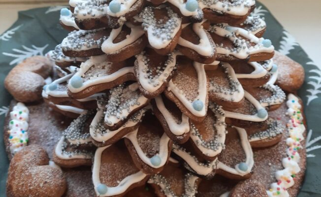 No dažāda izmēra piparkūkām veidota Ziemassvētku eglīte ar baltu glazūru.