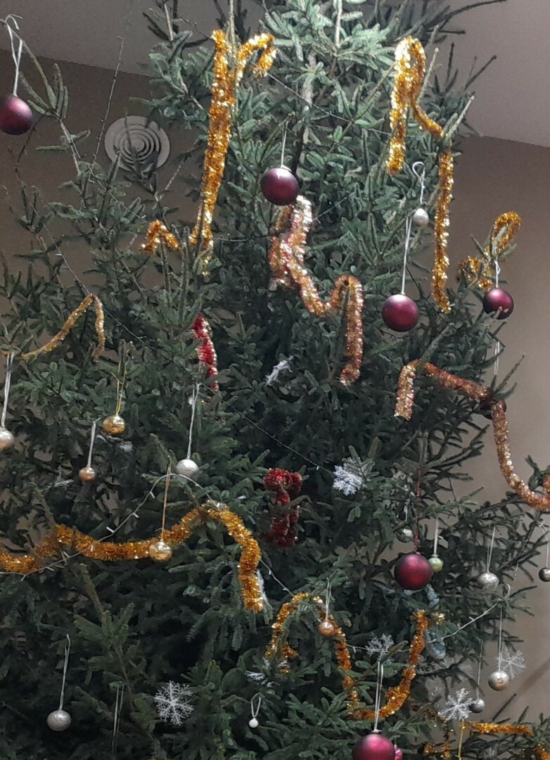 Izrotāta liela Ziemassvētku egle ar spožām vītnēm un bumbuļiem.