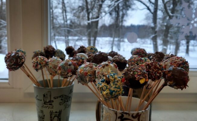 Šokolādes konfektes uz kociņa divās krūzēs.