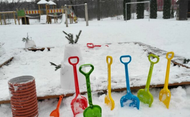 Krāsainas sniega lāpstiņas iedurtas baltā sniegā