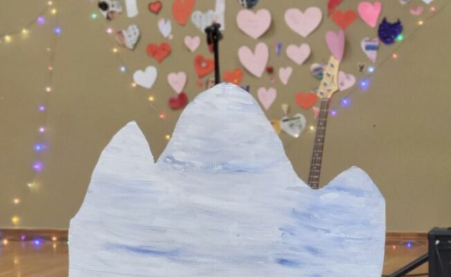 papīra sirsniņas pie sienas, uzraksts Popiela, dekorācijas - rotaļlietas pingvīni un kartona ledusgabals.