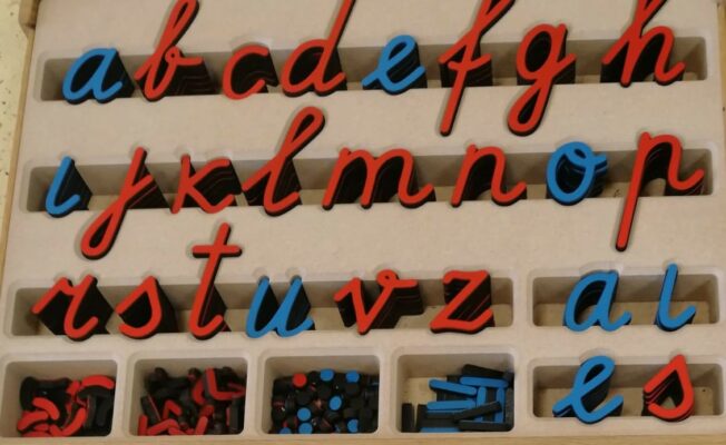 Rakstītie mazie latviešu valodas alfabēta burti koka kastē.