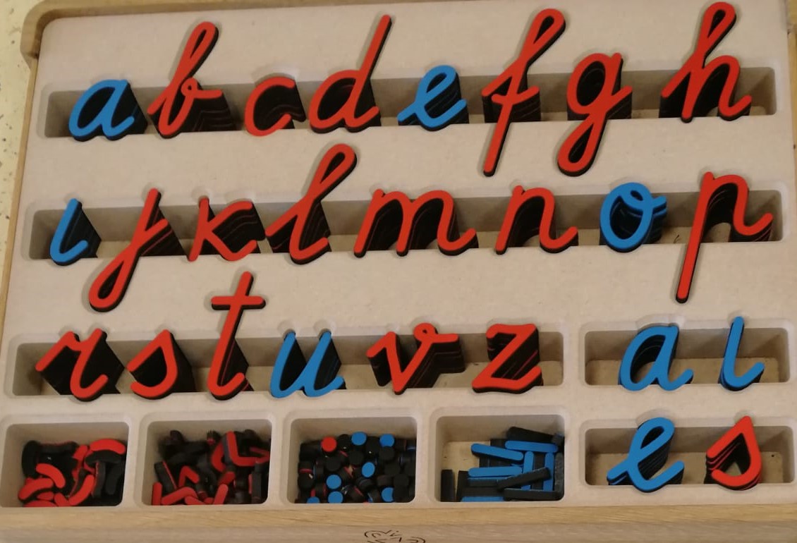 Rakstītie mazie latviešu valodas alfabēta burti koka kastē.