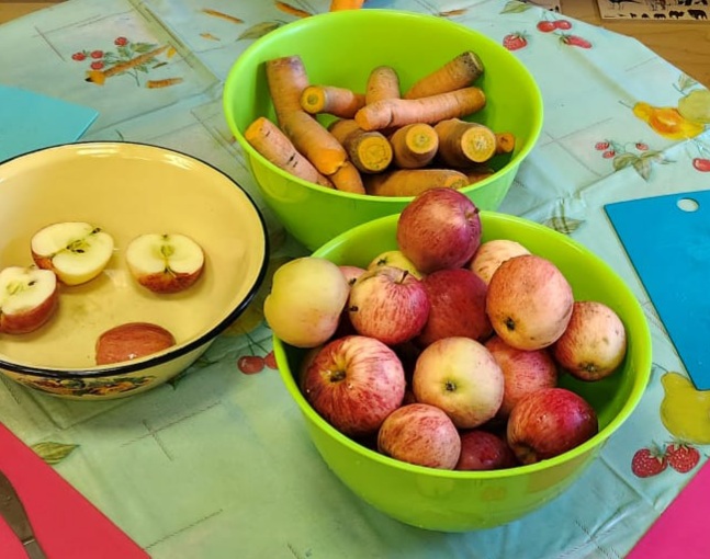 bļodās uz galda āboli un burkāni, daži āboli sagriezti