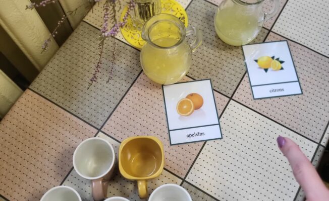 Krūzītes uz galda in divas stikla krūzes ar citronu un apelsīnu sulu