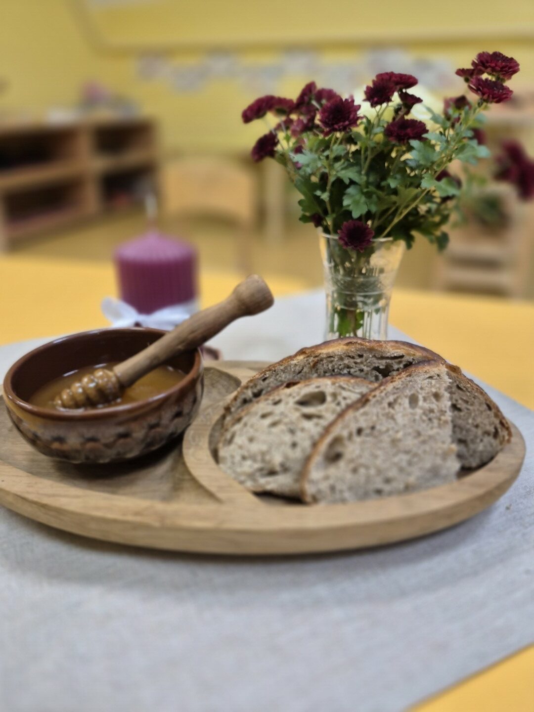 Koka paplātē maize, blakus tai māla bļodiņā medus