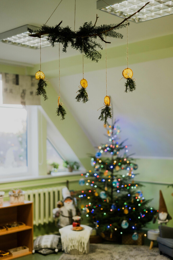 Izrotāta eglīte pie kuras nolikti rūķi