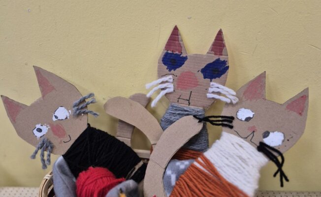 Groziņā bērnu gatavoti kaķu silueti aptīti ar dziju.