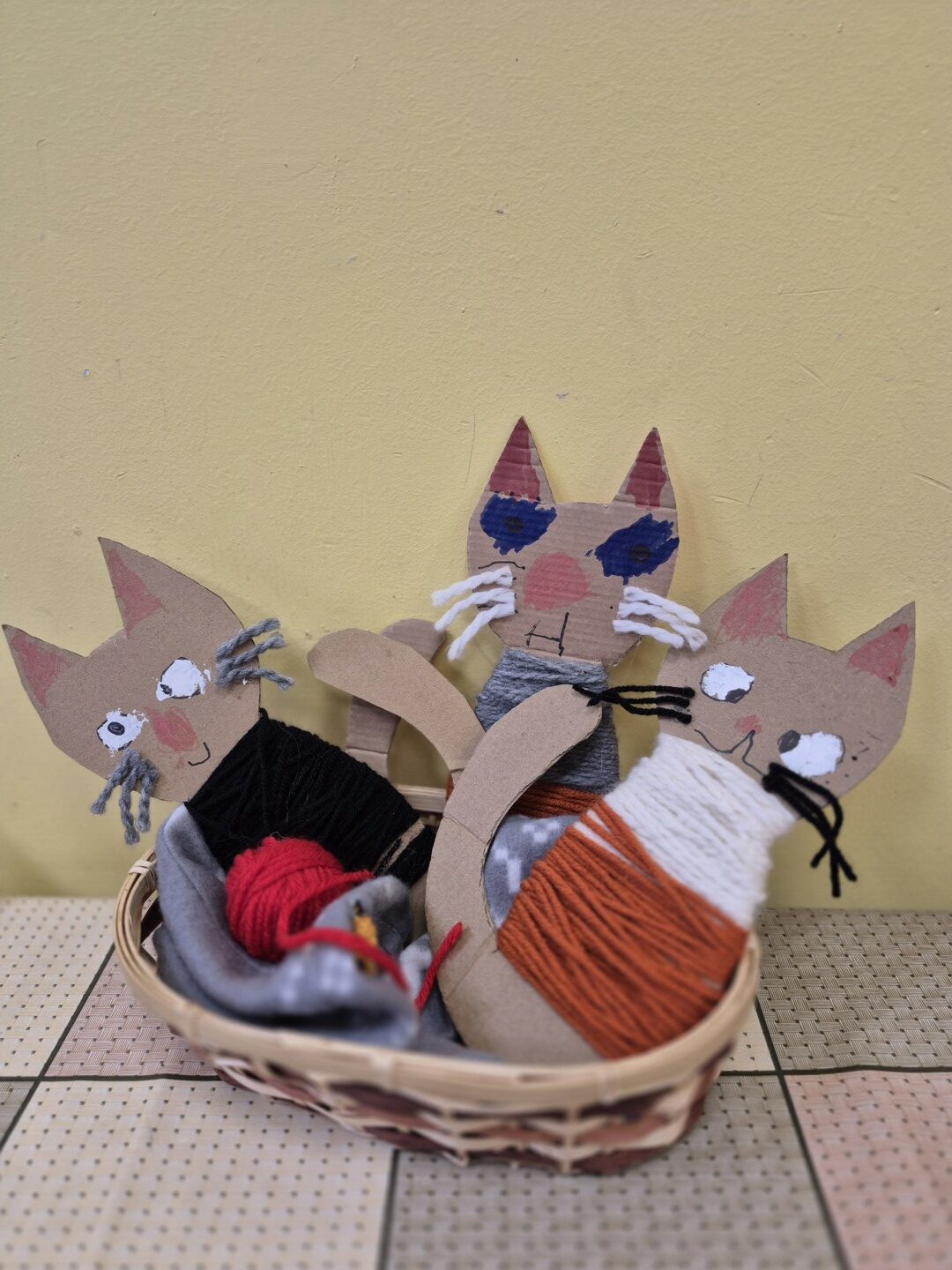 Groziņā bērnu gatavoti kaķu silueti aptīti ar dziju.