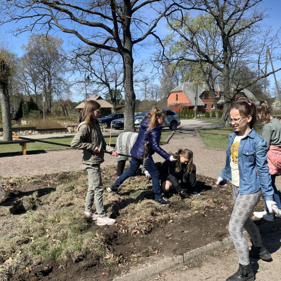 Skolēni un saimniecīte strādā dobē