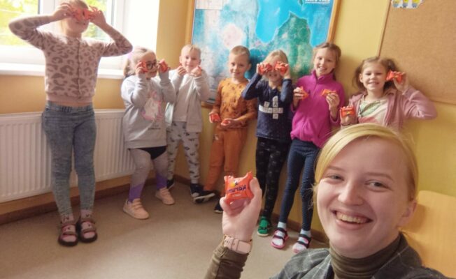 Bērni stāv klasē kopā ar skolotāju